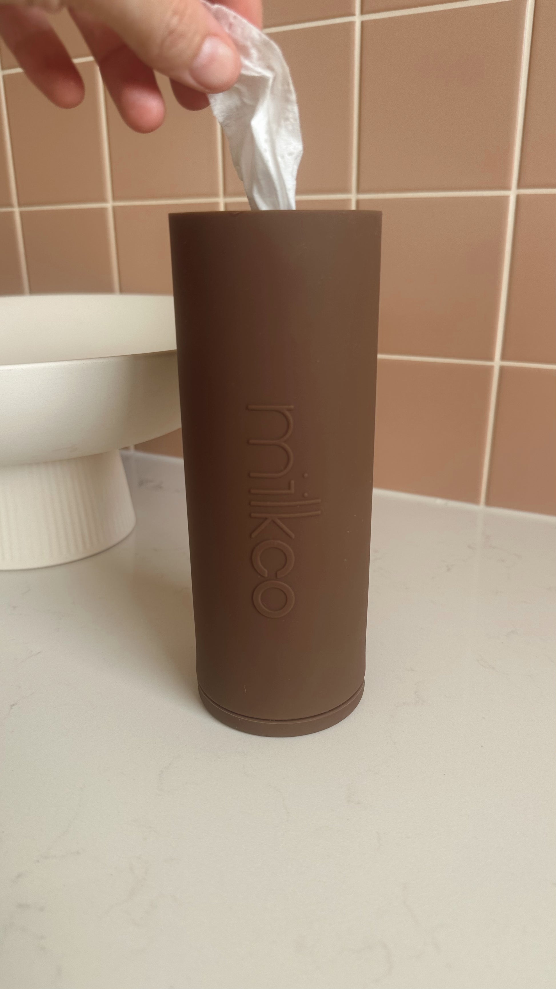 Brown cylindrical container with 'milkco' branding on a bathroom counter.